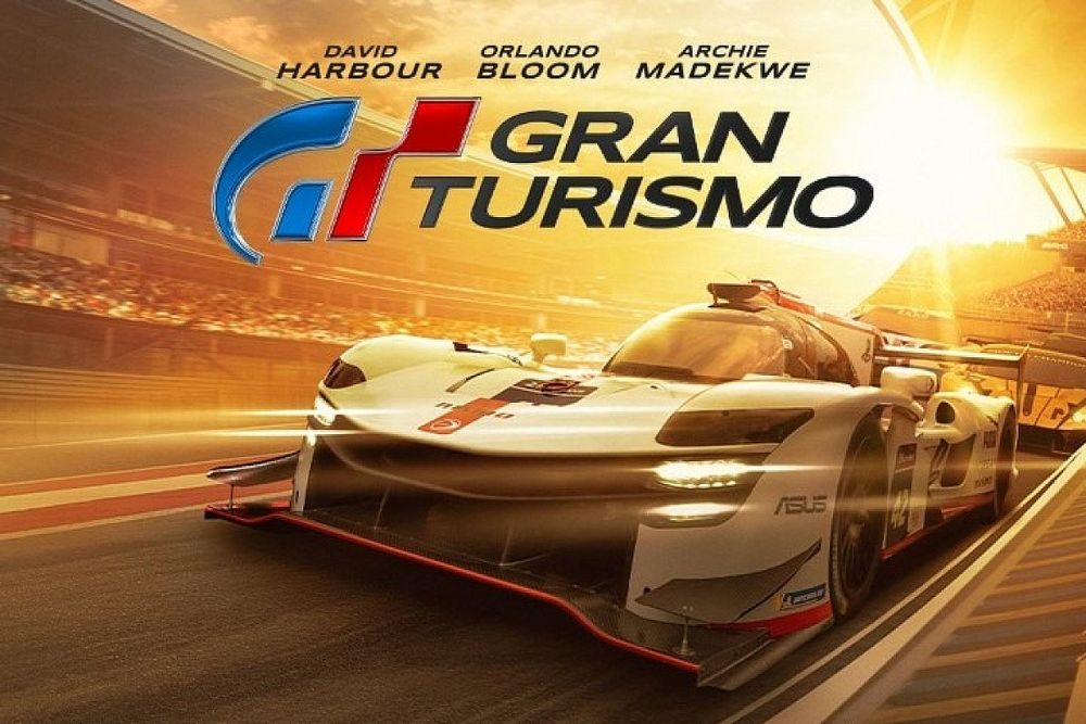 'Gran Turismo' es una adaptación digna de podio: un espectáculo audiovisual arrollador y emocionante gripado por los lugares comunes del género 'Gran Turismo' es una adaptación digna de podio: un espectáculo audiovisual arrollador y emocionante gripado por los lugares comunes del género Neill Blomkamp dirige la adaptación del mítico simulador de PlayStation con un sorprendente gusto por los efectos prácticos y el realismo Slack Imgs Los caminos de la industria de Hollywood son inescrutables. Es de sobra conocida la tendencia de la Meca del cine a la hora de explotar hasta la saciedad fórmulas de éxito como pueden ser las secuelas tardías —o legacy sequels—, los siempre socorridos remakes o las sagas interminables basadas en propiedades intelectuales consolidadas, pero, aún así, siempre queda espacio para la sorpresa. Entre las modas inagotables que llevan marcando la agenda de los grandes estudios desde hace una larga temporada se encuentran las siempre espinosas adaptaciones de videojuegos; un tipo de producciones indiscutiblemente prolíficas que siempre han sufrido al trasladar narrativas interactivas a un medio pasivo. Pero en la era de la explotación vía estudio de mercado, algo tan inusual como versionar un juego no narrativo es posible. Este es el caso de 'Gran Turismo'; el largometraje con el que Neill Blomkamp ha traducido al lenguaje cinematográfico la legendaria franquicia de Kazunori Yamauchi en un cóctel imprevisible y satisfactorio —aunque irremediablemente familiar— a medio camino entre el drama deportivo de manual, el biopic más terrenal y el espectáculo audiovisual marca de la casa. Más que coches Desde que se anunció con el consiguiente arqueo de cejas generalizado, la película de 'Gran Turismo' ha estado marcada por por la comprensible desconfianza frente a una adaptación de un material original sin trama alguna ni personajes preexistentes; pero la estrategia de abrazar la historia real del gamer reconvertido en piloto Jann Mardenborough ha terminado resultando lo suficientemente efectiva como para disipar el escepticismo. No obstante, para llegar al verdadero punto de inflexión que convierte la cinta en un entretenimiento más que digno de nuestro tiempo nos vemos obligados a pasar, atónitos, por un primer acto que se asemeja al típico casco de escudería sepultado bajo infinidad de pegatinas y serigrafías de sponsors. Y es que los primeros compases de 'GT', pese a plantar con corrección sus bases temáticas y narrativas, no deja de ser una suerte de segmento publicitario multimillonario que no ceja en su esfuerzo de recordarnos las virtudes de la obra de Yamauchi. Slack Imgs Afortunadamente, una vez superada esta vuelta de formación con aspecto de trámite más dilatado de la cuenta, el semáforo se tiñe de verde y el título pisa el acelerador para brindar dos actos narrados con gran pulso narrativo que explotan con acierto sus dos principales virtudes; todo ello mientras lucha infructuosamente por esquivar la sensación de déjà vu provocada por los numerosos lugares comunes del subgénero que no puede evitar recorrer. Es muy probable que hayamos visto 'Gran Turismo' con anterioridad en numerosas ocasiones; después de todo, no es la primera vez que nos enfrentamos al típico relato de sueños y aspiraciones truncados en la disciplina deportiva de turno. Pero la obra de PlayStation Studios se las apaña para traer algo de frescor a la trillada fórmula a través de un revulsivo que, por norma general, suele ser infalible: unos protagonistas con los que no es complicado empatizar. A pesar de estar construido mediante fórmulas arquetípicas, el dúo protagonista compuesto por el sufridor aspirante Jann y el curtido mentor con traumas anclados Jack hace gala de una dinámica en pantalla que sostiene por sí solo el peso del filme, escudada por la interpretación de un David Harbour que destaca con su derroche de carisma y que está tan entregado a la causa como inspirado. El segundo gran puntal de 'Gran Turismo', como cabría esperar, no es otro que su factura técnica y su impecable realización. Tratándose de un proyecto capitaneado por Neill Blomkamp, no deja de sorprender cómo el sudafricano ha priorizado lo práctico sobre los efectos visuales para trasladar de la forma más fidedigna posible las sensaciones que se experimentan al volante a 300 kilómetros por hora. Gran Turismo Drones FPV, Ultimate Arms, modelos de Nissan GT-R armados con cámaras para captar la acción a velocidad real... la cantidad de recursos empleados por Blomkamp y el director de fotografía Jacques Jouffret es tan extensa como efectiva, y sirve en bandeja de plata unos segmentos de conducción rodados en localizaciones reales que suponen la guinda en un pastel mucho más apetecible de lo que podría parecer en primera instancia. Está claro que 'Gran Turismo' no inventa la rueda. Las sencillas trazadas con las que recorre sus 135 extensos minutos están minadas de elementos vistos una y mil veces sorteados sin volantazos demasiado bruscos que alejen el conjunto de la línea segura y marcada, pero esta improbable versión del simulador de Polyphony Digital se las ha terminado apañando para subir al podio a base de emoción, encanto y garra audiovisual. En Espinof | Las 46 películas más esperadas y los mejores estrenos de 2023